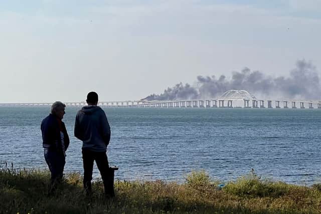 People look at thick black smoke rising from a fire on the Kerch bridge that links Crimea to Russia, after a truck exploded, near Kerch, on 8 October 2022 (Photo: ROMAN DMITRIYEV/AFP via Getty Images)
