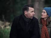 Craig Parkinson as George and Shirley Henderson as Claudia in The House Across the Street, sat by a tree and wrapped up warm (Credit: Channel 5/Clapperboard)
