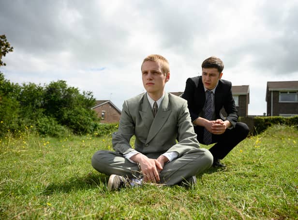 <p>Lewis Gribben as Danny and Samuel Bottomley as Aaron in Somewhere Boy, wearing suits and sat in the garden (Credit: Channel 4) </p>