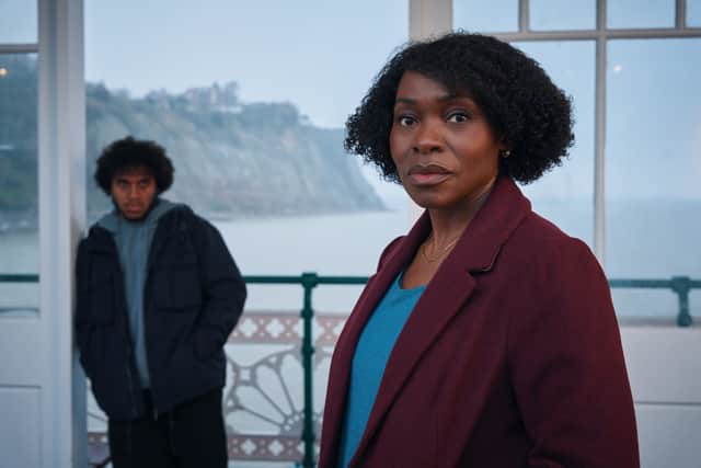 Rakie Ayoala as Christine, stood on a pier with Jordan Wilks as Connor in the background behind her (Credit: BBC/Little Door Productions/Simon Ridgway)