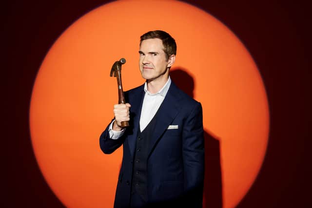 Jimmy Carr, holding a hammer aloft, illuminated on an orange background (Credit: Channel 4)