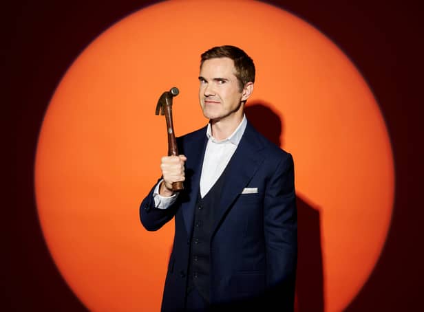 <p>Jimmy Carr, holding a hammer aloft, illuminated on an orange background (Credit: Channel 4)</p>