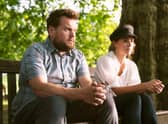 James Corden as Jamie Buckingham and Melia Kreiling as Amandine Buckingham, sat looking pensive on  park bench (Credit: Luke Varley)