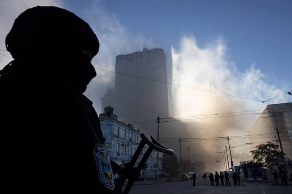 A member of the Ukrainian police force stands guard next to smoke as Kyiv is rocked by explosions during a drone attack in the early morning on 17 October 2022 (Photo: Paula Bronstein /Getty Images)