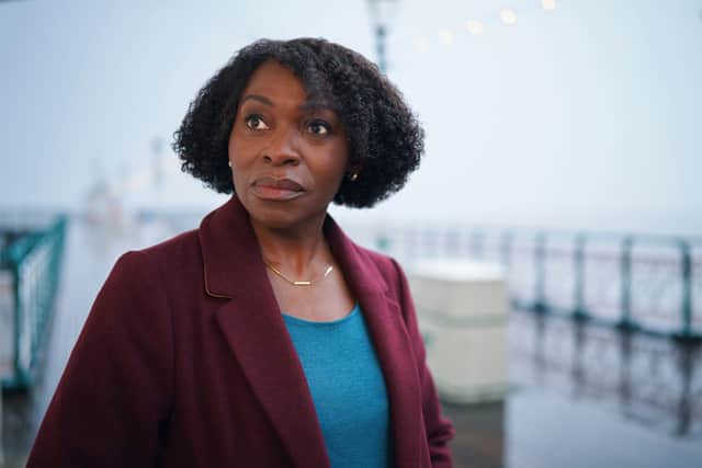 Rakie Ayola as Christine in The Pact S2, wearing a blue jumper and burgundy coat (Credit: BBC/Little Door Productions/Simon Ridgway)