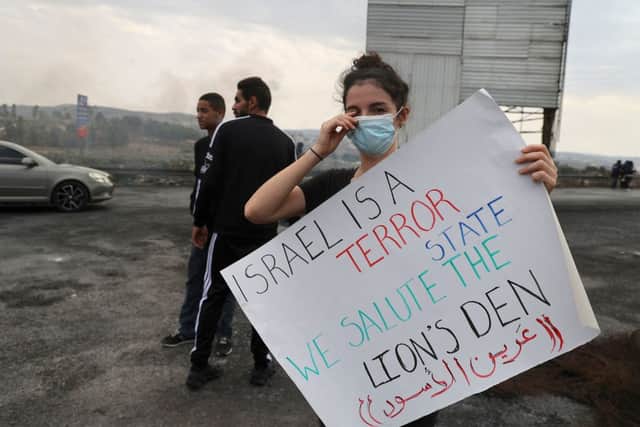 A Palestinian protester lifts a placard during a demonstration demanding the opening of roads around Nablus city, closed-off by the Israeli army since October 11. Credit: JAAFAR ASHTIYEH/AFP via Getty Images