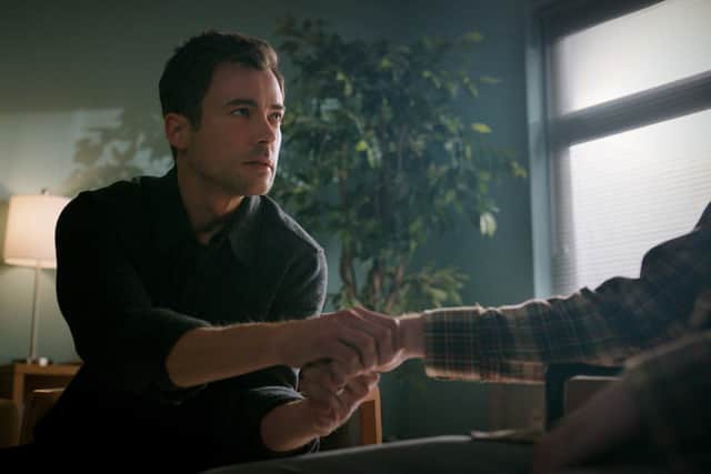 Matt Long as Zeke Landon in Manifest Season 4, holding a hospital patient’s hand (Credit: Netflix)
