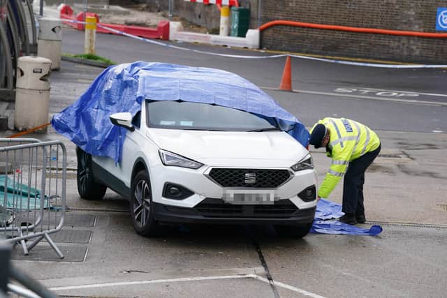 A police officer covers a car by the migrant centre in Dover, which was firebombed. Credit: PA