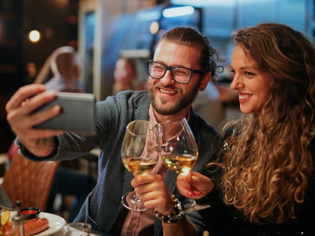 Couple sitting in restaurant at dinner and taking selfie (chika_milan - stock.adobe.com)