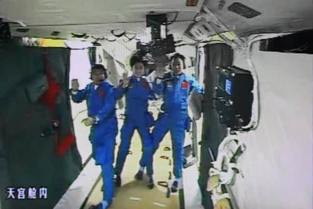 A photo of the giant screen at the Jiuquan space center shows three Chinese astronauts (from left) Liu Wang, Jing Haipeng and Liu Yang in the Tiangong-1 module on June 18, 2012.  Three Chinese astronauts entered an orbiting module for the first time, in a move broadcast live on China's state television network and a key step towards the nation's first space station.         CHINA OUT      AFP PHOTO        (Photo credit should read STR/AFP/GettyImages)