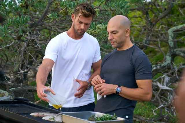 Chris Hemsworth and Peter Attia cook on a grill. (Credit: National Geographic for Disney+/Craig Parry)