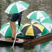 People shelter under umbrellas as they punt along the River Cam in Cambridge during a heavy rain shower. Picture date: Sunday November 6, 2022.