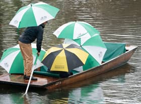 People shelter under umbrellas as they punt along the River Cam in Cambridge during a heavy rain shower. Picture date: Sunday November 6, 2022.