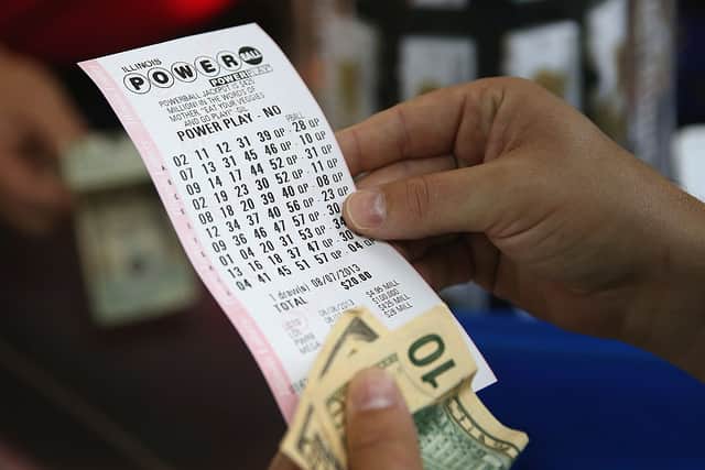 A customer at a 7-Eleven store checks the numbers on his Powerball lottery ticket on August 7, 2013 in Chicago, Illinois (Photo by Scott Olson/Getty Images)