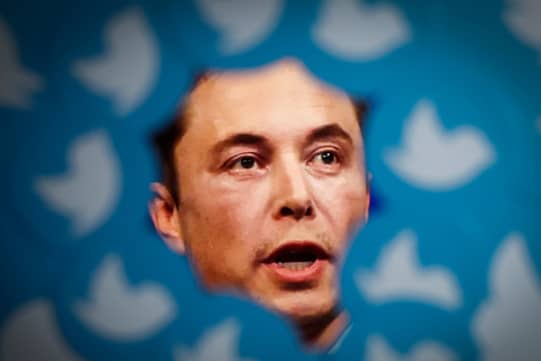 An image of new Twitter owner Elon Musk is seen surrounded by Twitter logos (Photo by STR/NurPhoto via Getty Images