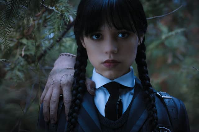 Jenna Ortega stars as Wednesday Addams in Wednesday, with her friend and severed hand Thing perched on her shoulder (Credit: Netflix)