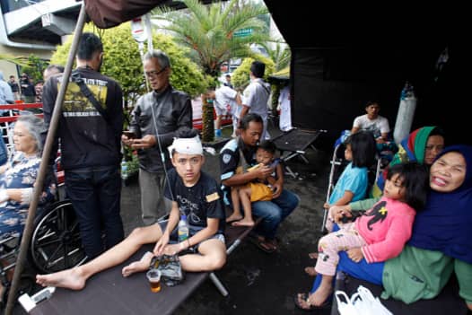 Wounded people rest under a tent displayed outside a hospital following an earthquake in Cianjur (AFP via Getty Images)