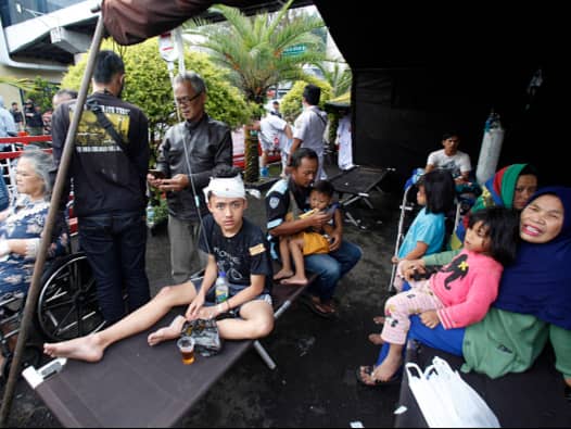 <p>Wounded people rest under a tent displayed outside a hospital following an earthquake in Cianjur (AFP via Getty Images)</p>