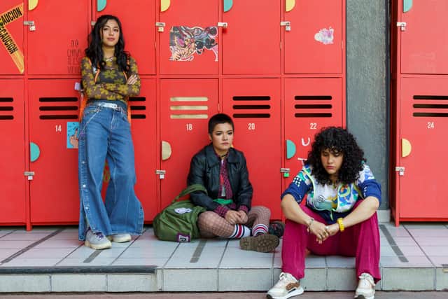 Esmeralda Soto as Mich, Isabel Yudice as Yadi, and Alicia Velez as Tania in The Most Beautiful Flower, sat by red school lockers (Credit: Amanda Safa/Netflix)