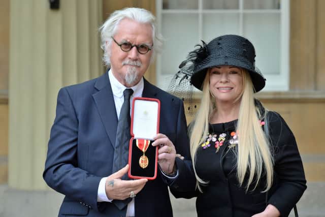 British comedian Billy Connolly poses with his medal next to his wife Pamela Stephenson after being knighted as a Knights Bachelor (knighthood) for services to entertainment and charity during an investiture ceremony at Buckingham Palace, London on October 31, 2017. / AFP PHOTO / POOL / John Stillwell (Photo credit: JOHN STILLWELL/AFP via Getty Images)