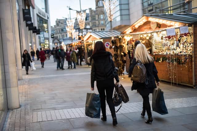 Members of the public carry their shopping by the stalls of the Manchester Christmas Market which is spread across the city centre in Manchester, northern England on November 9, 2018. - The annual Christmas Market entertains millions of visitors over the festive season with hundreds of market stalls selling food and drink as well Christmas gifts. (Photo by Oli SCARFF / AFP)        (Photo credit should read OLI SCARFF/AFP via Getty Images)