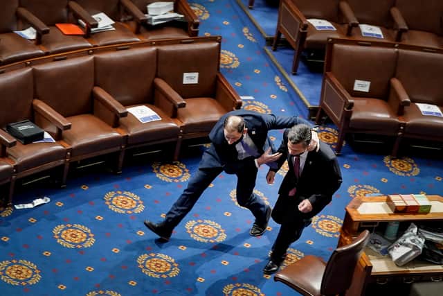 A member of the U.S. Capitol police rushes Rep. Dan Meuser (R-PA) out of the House Chamber as protesters try to enter the House Chamber on January 6 (Photo: Getty Images)
