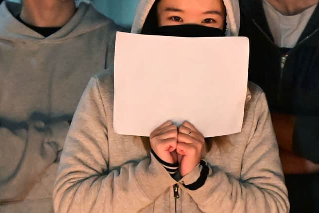 A woman holds a blank sheet of paper as demonstrators protest the deaths caused by an apartment complex fire in Urumqi, Xinjiang, China, at the Langson Library on the campus of the University of California, Irvine, in Irvine, California, on November 29, 2022. - Protests have broken out across China after the Urumqi fire occurred on November 24, 2022. Ten people were reported killed in an apartment building, with delayed fire response due to strict Covid lockdowns being blamed for the deaths. (Photo by Frederic J. BROWN / AFP) (Photo by FREDERIC J. BROWN/AFP via Getty Images)