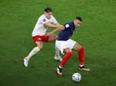 Kylian Mbappe is tackled by Poland’s Matty Cash