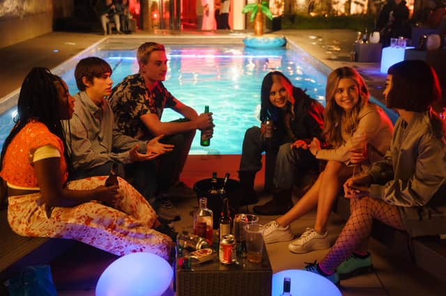 Lauryn Ajufo as Neve, Spike Fearn as Louis, Eden H. Davies as Jonny, Tessa Lucille as Regan, Carla Woodcock as Zia, and Callina Liang as Mei, drinking together by a swimming pool at night in Tell Me Everything (Credit: ITVX/Noho Film & Television)