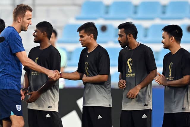 England’s forward Harry Kane (L) shakes hands with migrant workers during a meeting at the Al Wakrah Stadium in Doha. Credit: PAUL ELLIS/AFP via Getty Images