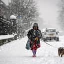 A woman walks a dog through the snow in Glasgow in 2021 (Photo: AFP via Getty Images)