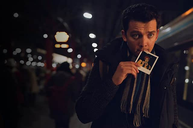 Asa Butterfield as James in Your Christmas or Mine, holding a polaroid in his mouth (Credit: Amazon Prime Video)