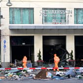 Workers of the city cleaning department walk past debris covering the street in front of the Radisson Blu hotel after a huge aquarium located in the hotel's lobby burst on December 16, 2022 in Berlin. - The 14-metre high AquaDom aquarium has burst and the leaking water has forced the closure of a nearby street, police and firefighters said. Berlin police said on Twitter that as well as causing "incredible maritime damage", the incident left two people suffering injuries from glass shards. The cylindrical aquarium contained over a million litres of water and was home to around 1,500 tropical fish. (Photo by John MACDOUGALL / AFP) (Photo by JOHN MACDOUGALL/AFP via Getty Images)