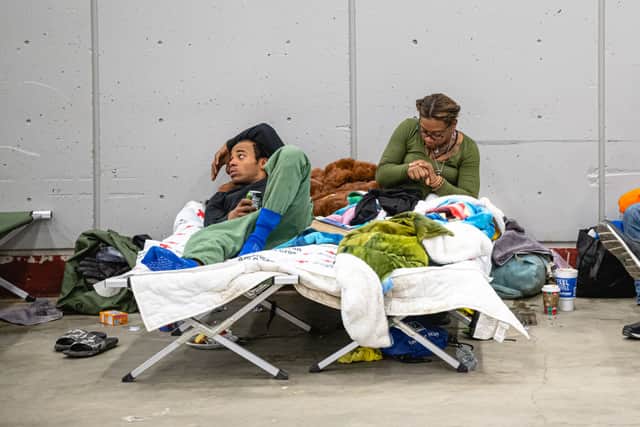 Devon and Grace, two homeless people, rest on cots at an emergency shelter in Broadbent Arena on December 24, 2022 in Louisville, Kentucky. Heavy winter precipitation and temperatures 40 degrees below average are expected throughout the Christmas weekend over much of the United States. (Photo by Jon Cherry/Getty Images)