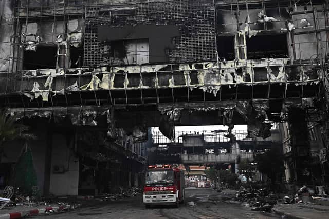 A police vehicle is pictured under a destroyed part of the Grand Diamond City hotel-casino following a major fire in Poipet on December 29, 2022. - About 10 people are dead and more than a dozen on life support after a fire at a Cambodian border casino, with photos from the scene showing people desperately huddled on ledges and perched on windowsills in a bid to escape the flames. (Photo by Lillian SUWANRUMPHA / AFP) (Photo by LILLIAN SUWANRUMPHA/AFP via Getty Images)