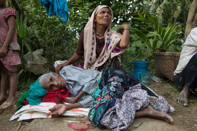Bhelua Khatun, age 70,  exhausted from his journey rests on the side of the road as his daughter Anwara ,45 looks for humanitarian aid after a new wave of Rohingya arrivals across the border by foot from Myanmar in 2017. Credit: Paula Bronstein/Getty Images