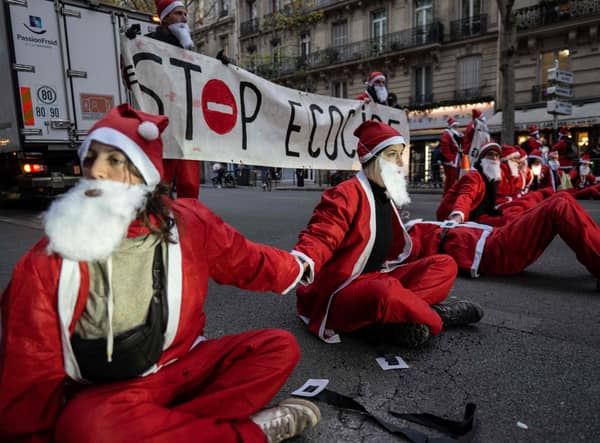 Extinction Rebellion activists dressed as Santa Claus sit on the Boulevard Saint-Germain outside the Ecological transition ministry in Paris, to denounce the government's environmental policy on the eve of the start in Montreal of the COP15 biodiversity summit in Paris, on December 6, 2022. (Photo by Anna KURTH / AFP) (Photo by ANNA KURTH/AFP via Getty Images)