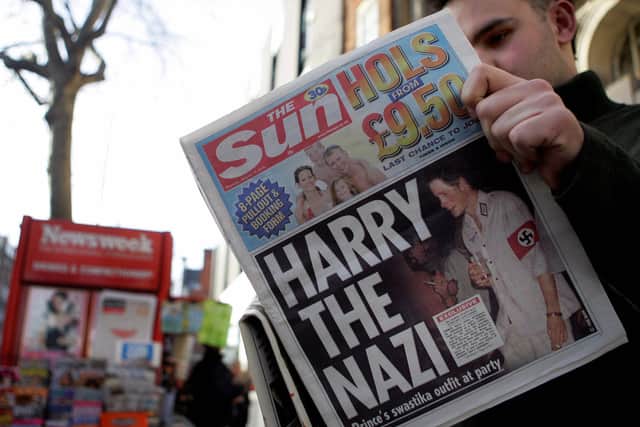 A man reads the newspaper “The Sun” in London 13 January, 2005 with a headline about Prince Harry wearing a Nazi uniform. (Photo credit should read JIM WATSON/AFP via Getty Images)