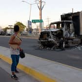 A man passes by a burnt truck on a street during an operation to arrest the son of Joaquin “El Chapo” Guzman, Ovidio Guzman, in Culiacan, Sinaloa state, Mexico (Photo: JUAN CARLOS CRUZ/AFP via Getty Images)
