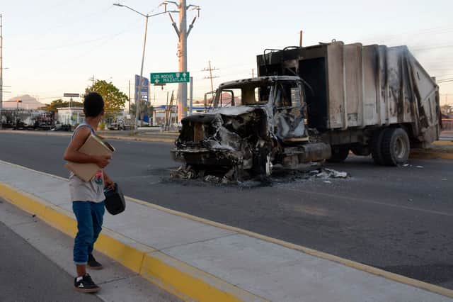<p>A man passes by a burnt truck on a street during an operation to arrest the son of Joaquin “El Chapo” Guzman, Ovidio Guzman, in Culiacan, Sinaloa state, Mexico (Photo: JUAN CARLOS CRUZ/AFP via Getty Images)</p>