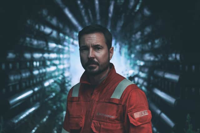 Martin Compston as Fulmer Hamilton in The Rig, wearing an orange boiler suit and surrounded by pipes (Credit: Amazon Prime Video)