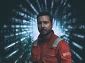 Martin Compston as Fulmer Hamilton in The Rig, wearing an orange boiler suit and surrounded by pipes (Credit: Amazon Prime Video)