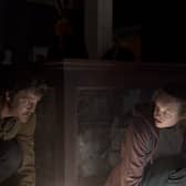 Pedro Pascal as Joel and Bella Ramsay as Ellie in The Last of Us, hiding from an Infected person in the dark (Credit: HBO)