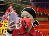 Girl holds phone with face mask on celebrating Chinese New Year (Getty Images)