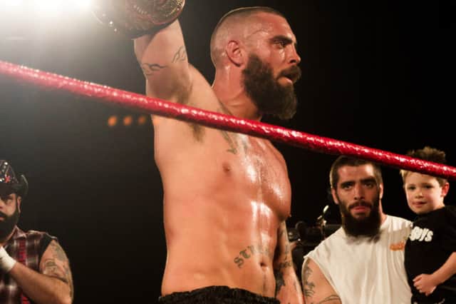 Jay Briscoe holds the ROH World Championship aloft as brother Mark looks on (Photo: Flickr/Wikimedia Commons)