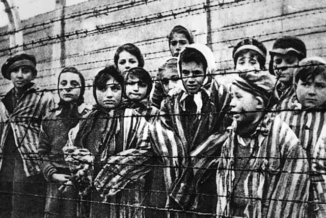 A group of child survivors behind a barbed wire fence at the Nazi concentration camp at Auschwitz-Birkenau on liberation day. 