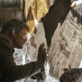 Pedro Pascal as Joel in The Last of Us, looking through a newspaper-covered window (Credit: HBO)