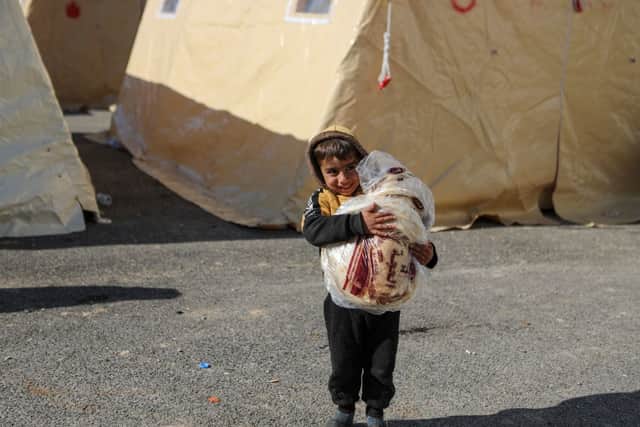 A Syrian child carries bread at a make-shift shelter for people who were left homeless, near the rebel-held town of Jindayris on February 9, 2023, two days after a deadly earthquake hit Turkey and Syria.   (Photo by AAREF WATAD/AFP via Getty Images)