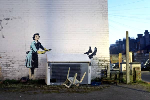 A new work by Banksy has appeared in Kent, which appears  to show a 1950’s housewife, wearing a classic blue pinny and yellow washing up gloves, with a swollen eye and a missing tooth seemingly shoving her male partner into a chest freezer (Photo: PA Media).