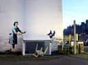 A new work by Banksy has appeared in Kent, which appears  to show a 1950’s housewife, wearing a classic blue pinny and yellow washing up gloves, with a swollen eye and a missing tooth seemingly shoving her male partner into a chest freezer (Photo: PA Media).